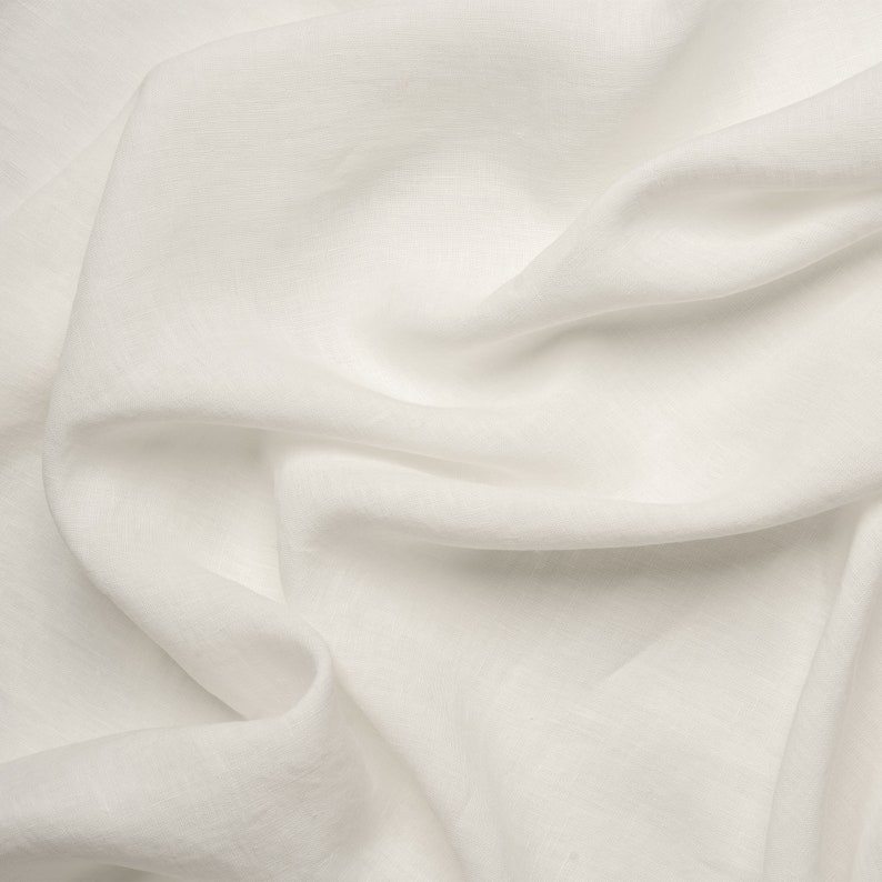 May include: White linen fabric with soft folds and wrinkles. The fabric is smooth and has a subtle texture.
