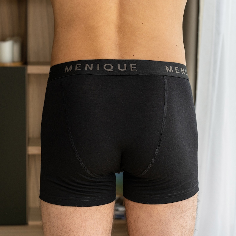 K&ouml;nnte beinhalten: Schwarze Boxershorts mit dem Wort "MENIQUE" auf dem Bund.