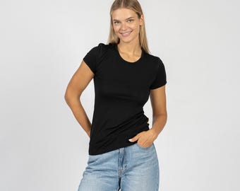 Può includere: Una donna indossa una maglietta nera a maniche corte e jeans blu chiaro.