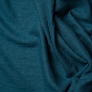 May include: A close-up of a teal blue fabric with a wrinkled texture. The fabric is soft and has a subtle sheen.