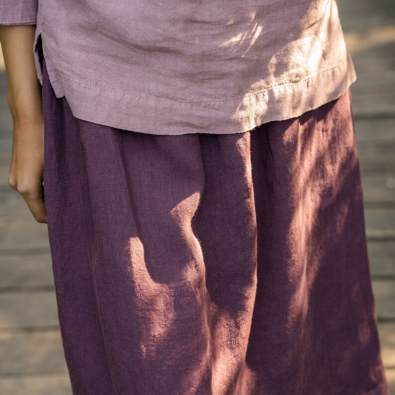 The model is wearing the SOPHIA skirt in shadow purple. This is a close-up of the skirt's 100% linen fabric in shadow purple color. It has an elegant texture.