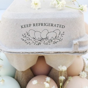 May include: A cardboard egg carton with a black and white illustration of eggs in a nest with the text 