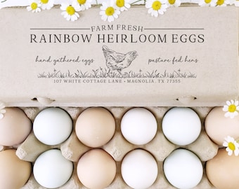 May include: A cardboard egg box filled with a variety of coloured eggs. The box has a label that reads "FARM FRESH - RAINBOW HEIRLOOM EGGS" with the text "hand gathered eggs" and "pasture fed hens" below. The label also includes the address "107 WHITE COTTAGE LANE - MAGNOLIA, TX 77355".