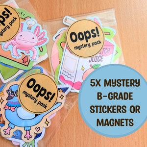 Puede incluir: Varios paquetes de pegatinas o imanes, cada uno en un embalaje transparente y etiquetado como "Oops! mystery pack". Las pegatinas presentan diseños de dibujos animados de un ajolote, una paloma y una caja de jugo de melocotón. También es visible un círculo azul con texto.