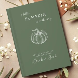 May include: A sage green hardback guest book featuring a white line drawing of a pumpkin in the centre. The text reads: a little PUMPKIN is on the way, LEAVE A MESSAGE FOR FUTURE PARENTS, and the names Sarah & Jack in a white script font.