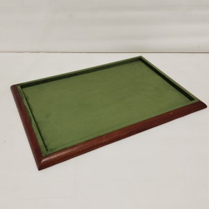 May include: A rectangular wooden tray with a green velvet lining. The tray has a dark brown wood frame and a smooth surface.