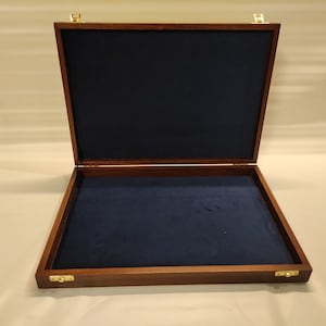May include: A dark brown wooden box with a blue velvet interior. The box has brass hinges and clasps.