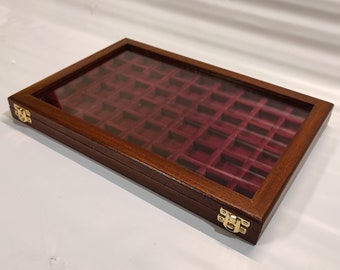 Op de afbeelding: Een houten displaykast met een glazen bovenkant en een rood fluwelen interieur. De kast heeft twee messing sluitingen en is ontworpen om kleine voorwerpen, zoals munten of sieraden, te bewaren.