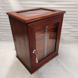 May include: A wooden cabinet with a glass door and multiple drawers. The cabinet is a dark reddish-brown color and has a keyhole and a tassel.