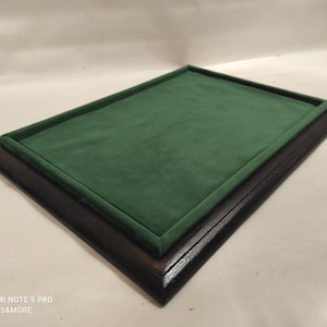 Peut inclure: Un présentoir rectangulaire avec un cadre en bois brun foncé et un intérieur en velours vert. Le plateau est conçu pour contenir et présenter des objets. Le cadre a une finition brillante.