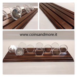 May include: A wooden coin display with clear plastic coin holders. The display has four rows and is stained a dark brown color. The display is perfect for showcasing your favorite coins.