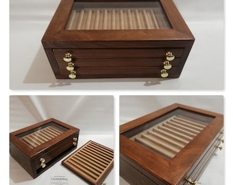 Könnte beinhalten: Eine Holzstiftebox mit Glasdeckel und drei Schubladen. Die Box ist aus dunklem Holz mit hellem Holzinnenraum. Die Schubladen haben Messingknöpfe.