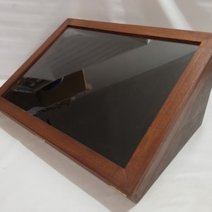 Op de afbeelding: Een houten vitrine met een glazen bovenkant. De vitrine is schuin en heeft een donkerhouten afwerking.