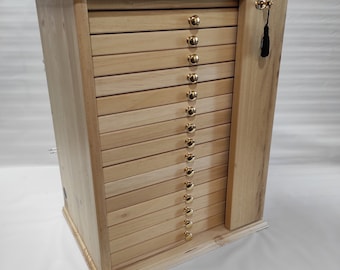 Könnte beinhalten: Ein Holzschränkchen mit 16 Schubladen und einer kleinen Tür auf der rechten Seite. Die Schubladen haben goldene Knöpfe und die Tür hat einen kleinen schwarzen Quasten.