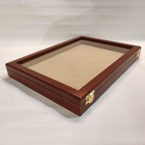 Op de afbeelding: Een houten displaykast met een glazen bovenkant en messing scharnieren. De kast is gevoerd met bruin vilt en is ideaal voor het tentoonstellen van kleine voorwerpen.