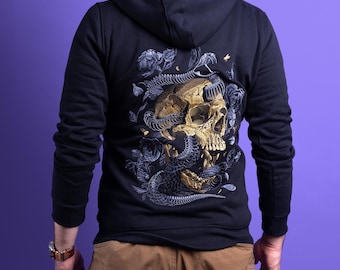 May include: A black hooded sweatshirt featuring a large, detailed back graphic of a golden skull intertwined with a dark, scaled serpent and surrounded by grey floral elements. The long-sleeved garment includes a hood and ribbed cuffs.