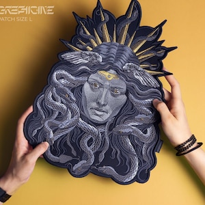 Può includere: Un patch ricamato nero e oro con una donna con serpenti nei capelli. Il patch ha il testo "GREFICINE PATCH SIZE L" in alto.