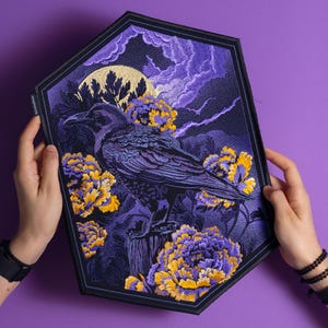 Puede incluir: Parche bordado de cuervo con luna llena, nubes y flores amarillas y moradas. El cuervo está posado en un poste de madera. El parche tiene un borde negro y se sostiene sobre un fondo morado.