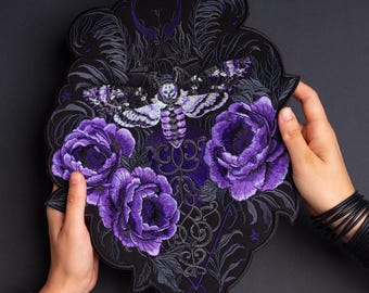 May include: A large embroidered patch featuring a central death's-head hawkmoth in shades of purple, white, and black. The moth is surrounded by three vibrant purple peony flowers, intricate dark foliage, and decorative filigree patterns.