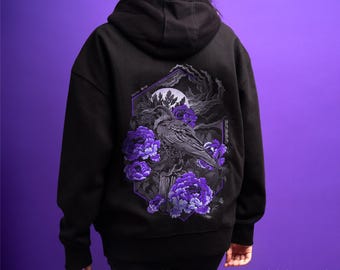 May include: A black hooded sweatshirt featuring a detailed graphic on the back. The design displays a raven perched on a branch surrounded by vibrant purple peony flowers, a full moon, and dark clouds, all enclosed within a geometric frame.