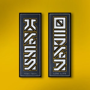 May include: Two rectangular patches with black borders and a textured background. Each patch features a stylized design in white and yellow, with the words "HIGH TECH" and "LOW LIFE" at the bottom. The background is a solid yellow.