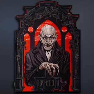 Pode incluir: Um patch retangular com uma ilustração detalhada do personagem Nosferatu. A imagem mostra o vampiro com traços marcantes, dedos longos e um casaco preto, contra um fundo vermelho. A palavra "NOSFERATU" é exibida na parte inferior.