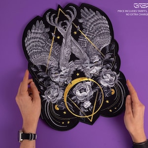 以下が含まれることがあります： 黒いパッチ。2羽のフクロウ、花の要素、金と白の幾何学模様の詳細なイラスト。パッチはスカラップエッジで、紫色の背景に保持されています。