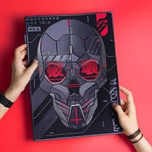 May include: Black and grey embroidered patch featuring a futuristic skull design. The skull has red eyes and a red cross on the forehead. The text "PROTOTYPE UNIT 1313" is printed on the patch.