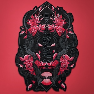 Puede incluir: Parche bordado negro con diseño gótico. Presenta dos cuervos, rosas rojas y el texto "IN MEMORY OF SHIT WHEN I GAVE A". El parche tiene un borde negro y está sobre un fondo rojo.