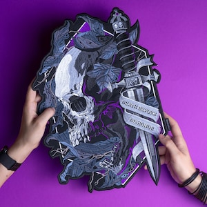 Può includere: Una toppa ricamata in bianco e nero con un teschio, un pugnale e uno stendardo che recita "Death Before Dishonor". La toppa è circondata da uno sfondo viola.