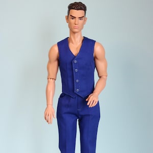 Puede incluir: Muñeco vestido con chaleco azul y pantalón a juego, con zapatos negros. El chaleco tiene cuello en V y cierre de botones. El muñeco tiene cabello castaño y está de pie frente a un fondo azul claro. El atuendo es de estilo clásico y a medida.