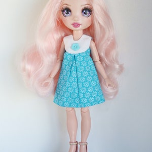 May include: A doll with pink hair wearing a blue and white floral dress and white shoes with pink accents.