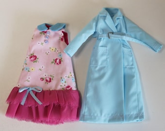 Könnte beinhalten: Zwei Puppenkleider, eines rosa mit Blumenmuster und einem Rüschen-Saum, das andere hellblau mit Gürtel und Taschen.