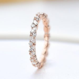 May include: A rose gold band ring with a delicate, pave setting of marquise-shaped diamonds.