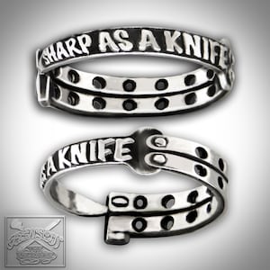 Könnte beinhalten: Ein silberner Ring mit der Gravur "Sharp as a Knife". Der Ring ist offen und hat einen Scharnierverschluss.