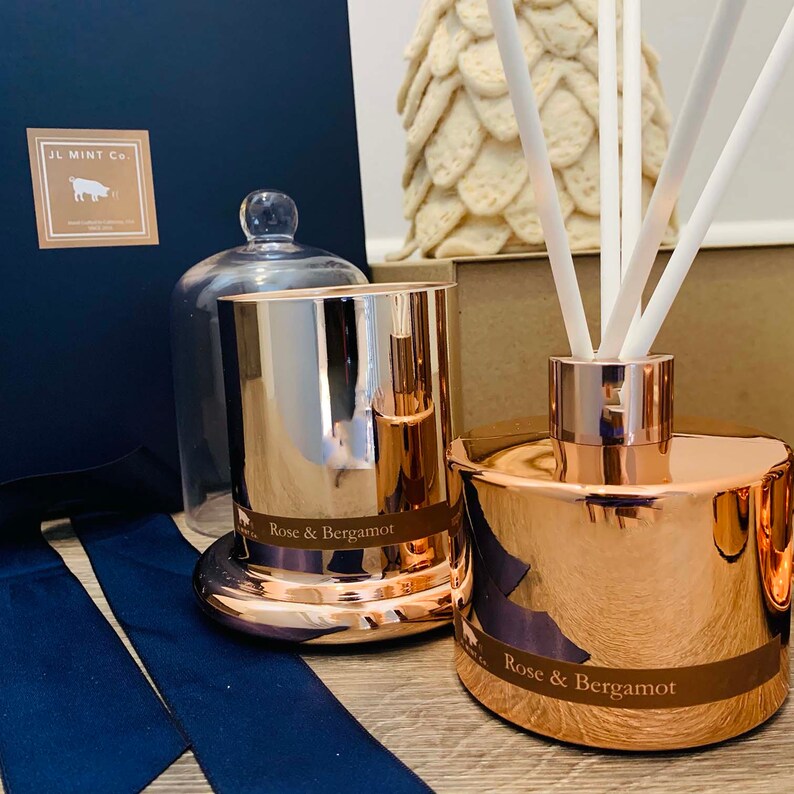 Puede incluir: Un conjunto de dos productos de fragancia para el hogar con aroma a rosa y bergamota. Una vela dorada con tapa de vidrio y un difusor dorado con ca&ntilde;as blancas. Ambos productos tienen una etiqueta que dice "Rose & Bergamota".