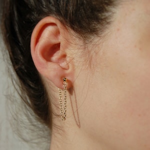 A medium-length loop of thin 18 karat gold plated chain wraped from the front to the back of the ear in the form of a threader earring, secured by 18 karat gold clip-on ball posts which are hypoallergenic, nickel-free, and clear invisible acrylic.