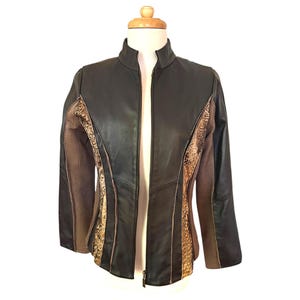 May include: A brown leather jacket with a zipper closure and a brown and gold patterned design on the front and sleeves.