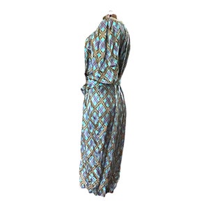 K&ouml;nnte beinhalten: Ein blaues und goldenes kariertes Wickelkleid mit langem Rock und Dreiviertel&auml;rmeln.