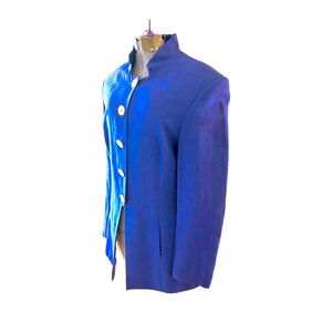 Puede incluir: Un blazer azul cobalto con cuello mao y botones blancos. La chaqueta entallada presenta un aspecto ligeramente texturizado, lo que sugiere una tela de alta calidad. El blazer se exhibe en un maniquí sobre un fondo blanco.
