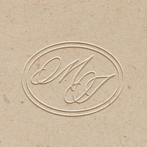 May include: A light tan, textured paper surface featuring a centered, embossed oval emblem. Inside the oval, the stylized, interconnected cursive letters M and J are debossed, creating a subtle, monochromatic, and tactile visual effect.
