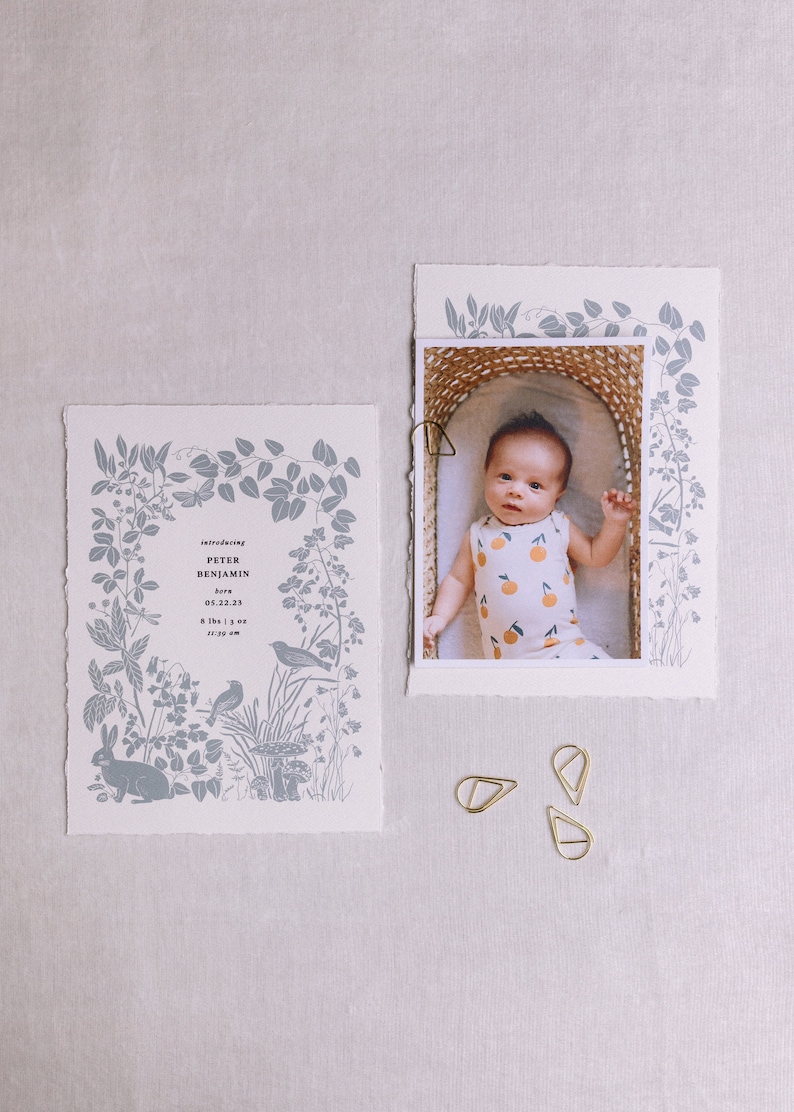 Puede incluir: Una tarjeta blanca con un borde floral azul y el texto "Introducing Peter Benjamin born 05.22.23 8:39 am"  Una foto de un beb&eacute; en una cesta con un mono blanco y naranja.