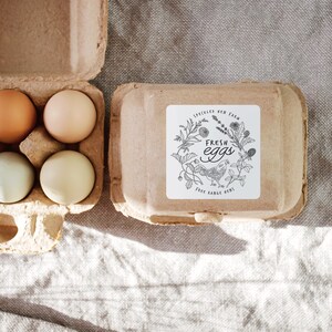 Op de afbeelding: Een kartonnen eierdoos met zes bruine en witte eieren. De doos heeft een sticker met de tekst "Speckled Hen Farm Fresh Eggs Free Range Hens".