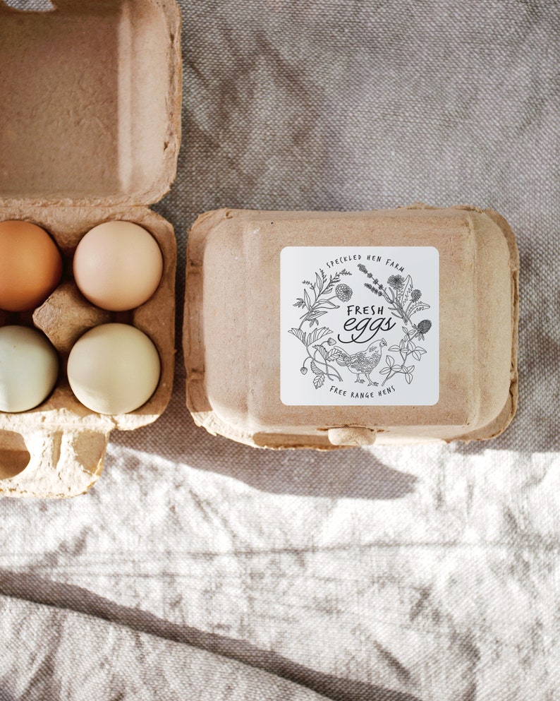 Op de afbeelding: Een kartonnen eierdoos met zes bruine en witte eieren. De doos heeft een sticker met de tekst "Speckled Hen Farm Fresh Eggs Free Range Hens".