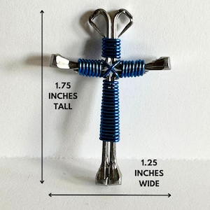May include: A blue and silver metal cross made from horseshoe nails. The cross is 1.75 inches tall and 1.25 inches wide.
