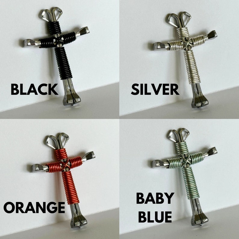 May include: Four handmade crosses crafted from horseshoes, each featuring a different coloured wire wrap. The crosses are black, silver, orange, and baby blue.
