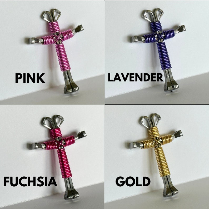 May include: Four handmade crosses made from horseshoe nails, each wrapped in a different colour wire: pink, lavender, fuchsia, and gold.