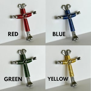 May include: Four handmade crosses made from horseshoes and wire. The crosses are red, blue, green, and yellow.