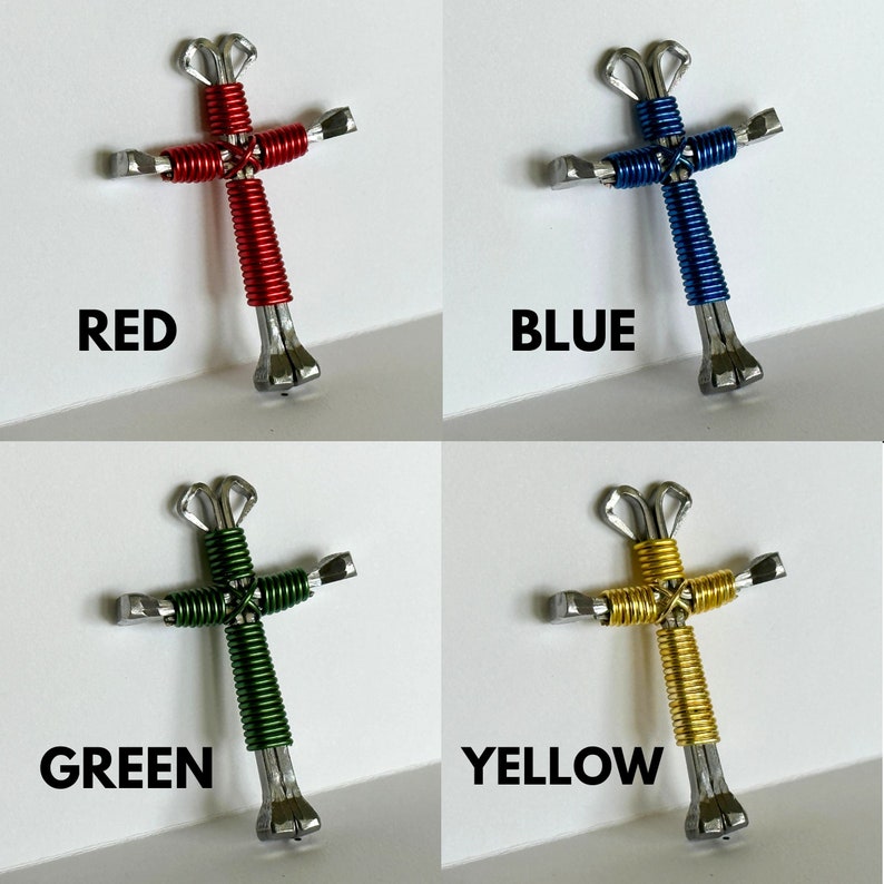 May include: Four handmade crosses made from horseshoes and wire. The crosses are red, blue, green, and yellow.