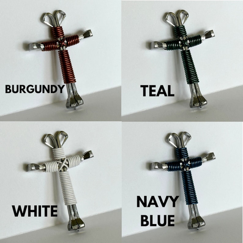 May include: Four handmade crosses made from horseshoe nails, each with a different coloured wire wrap. The crosses are burgundy, teal, white, and navy blue.